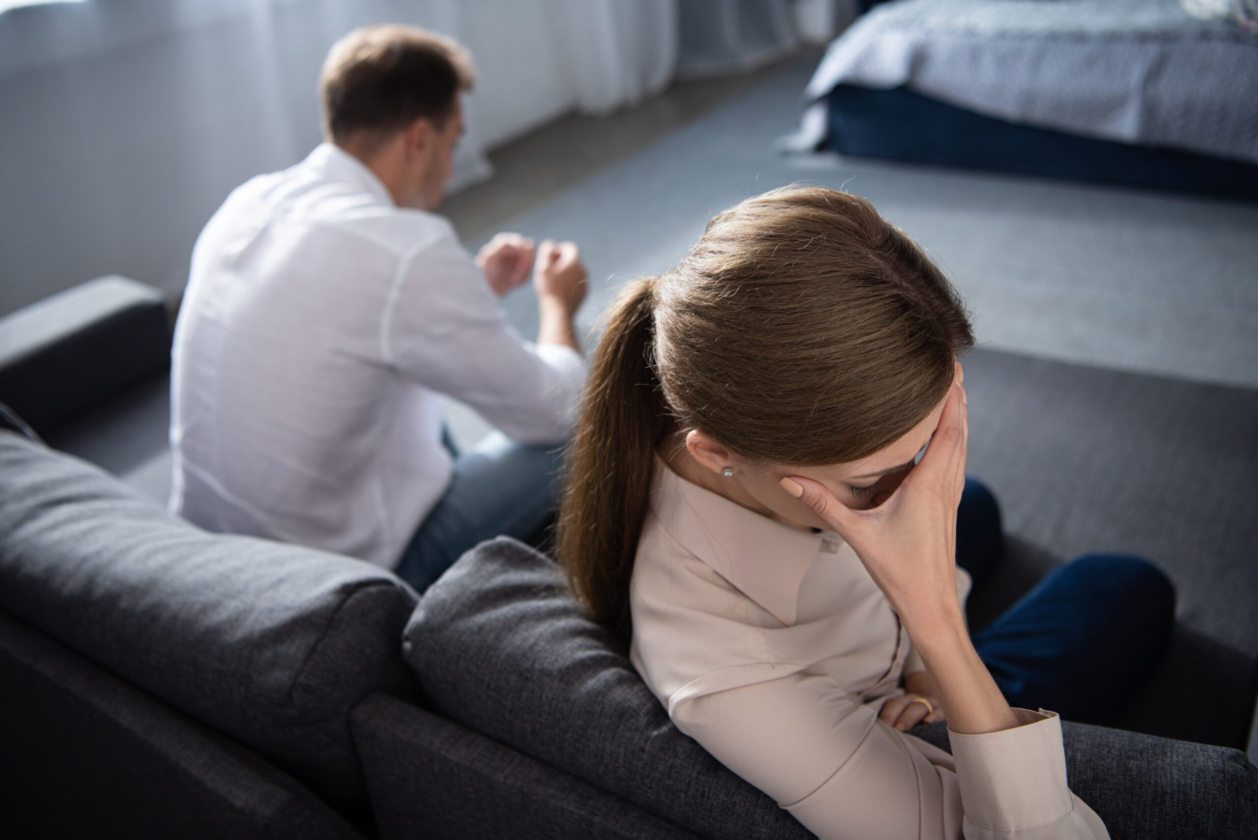 pensive upset couple in living room at home