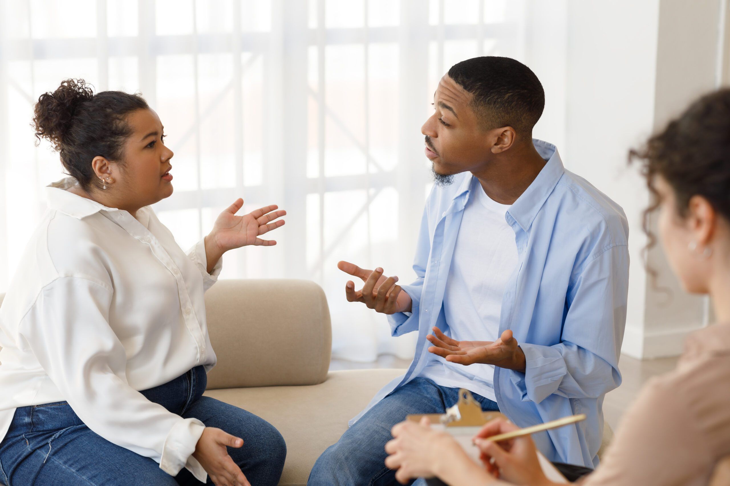 Hysterical emotional young black man and hispanic chubby woman yelling and gesturing, mixed race spouses fight at family counselor office. Marital crisis, marriage counseling concept
