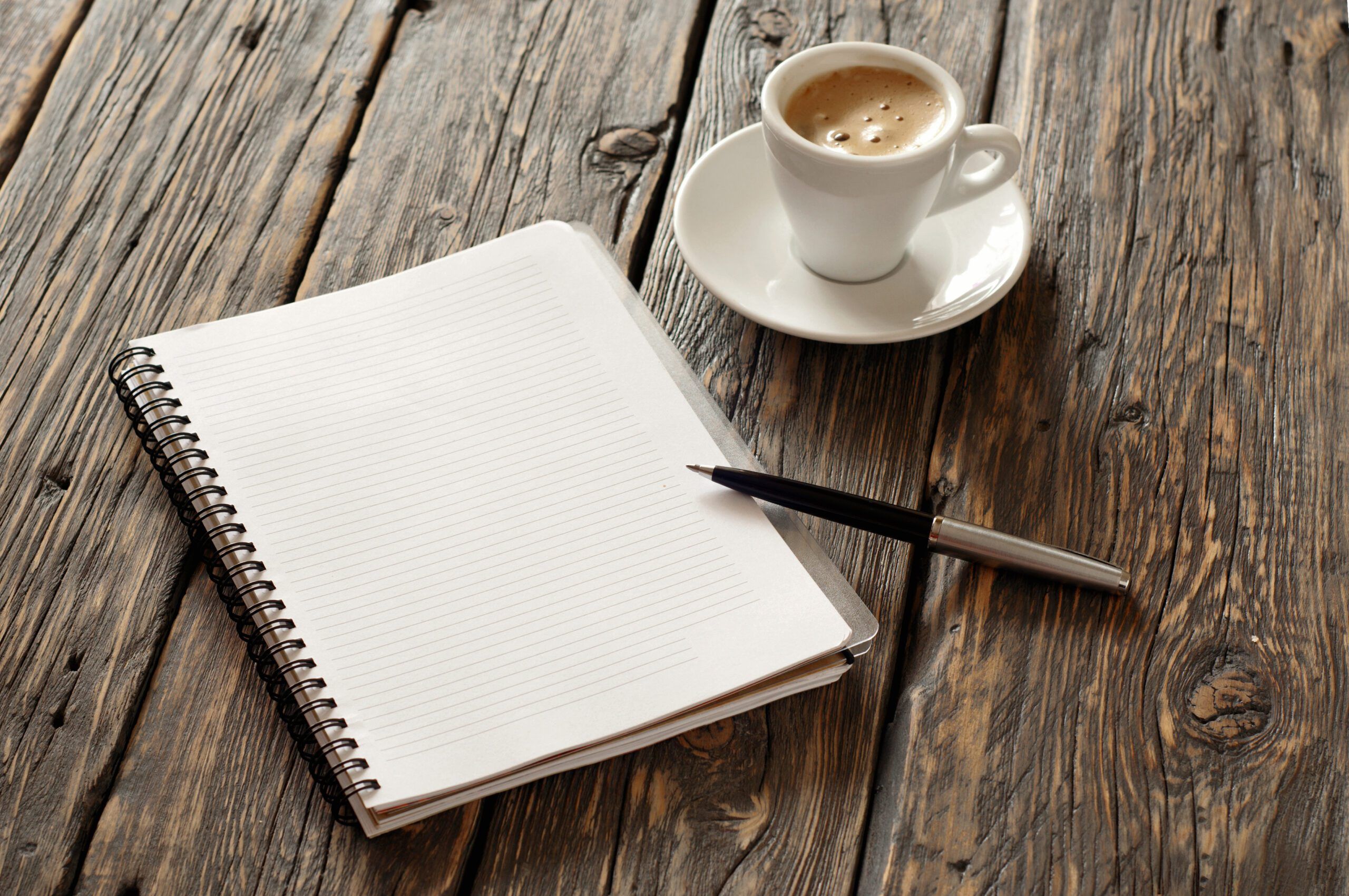 open notebook with blank pages and pen with cup of coffee espresso on the dark wooden surface, top view