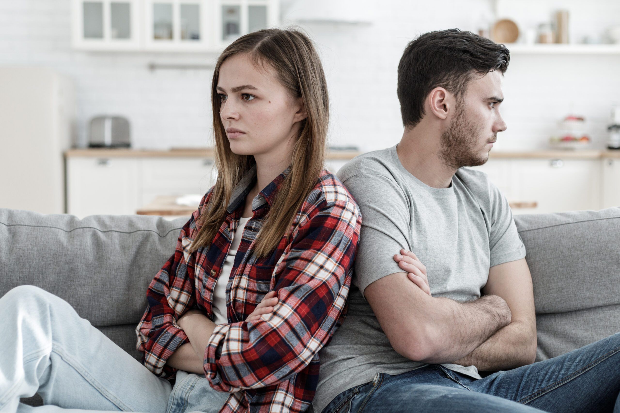 European couple experiencing problems in relations sitting next to each other but unwilling to communicate