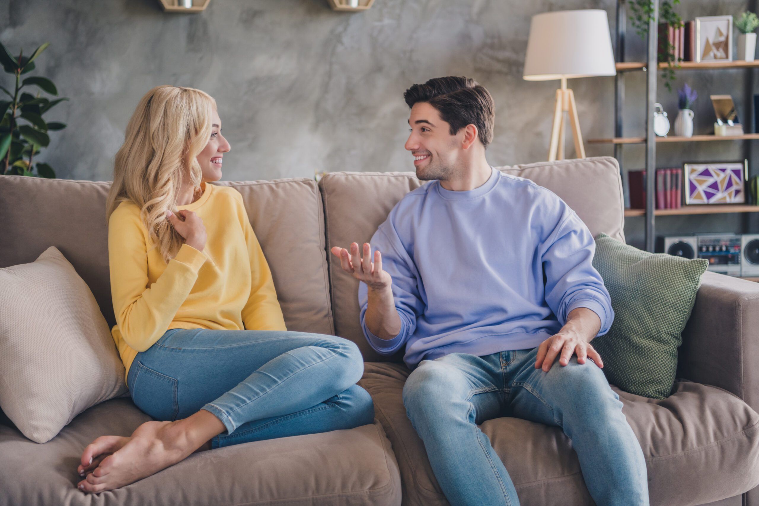 Photo of pretty cute young couple wear casual outfits smiling sitting couch communicating indoors house room